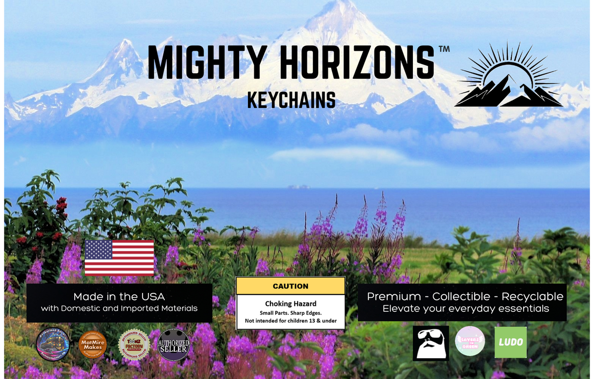 Mighty Horizons Keychains northern retail display sign with snowcapped mountains and wildflowers, U.S.-made materials statement, choking-hazard warning for ages 13 and under, premium collectible recyclable message, and designer attribution logos.