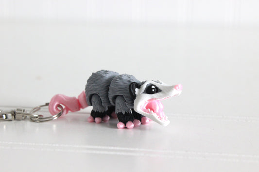 3D-printed gray-and-white opossum keychain with a silver swivel quick-clip on a white background.