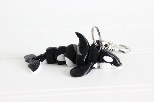 3D-printed black-and-white orca keychain with a silver swivel quick-clip on a white background.