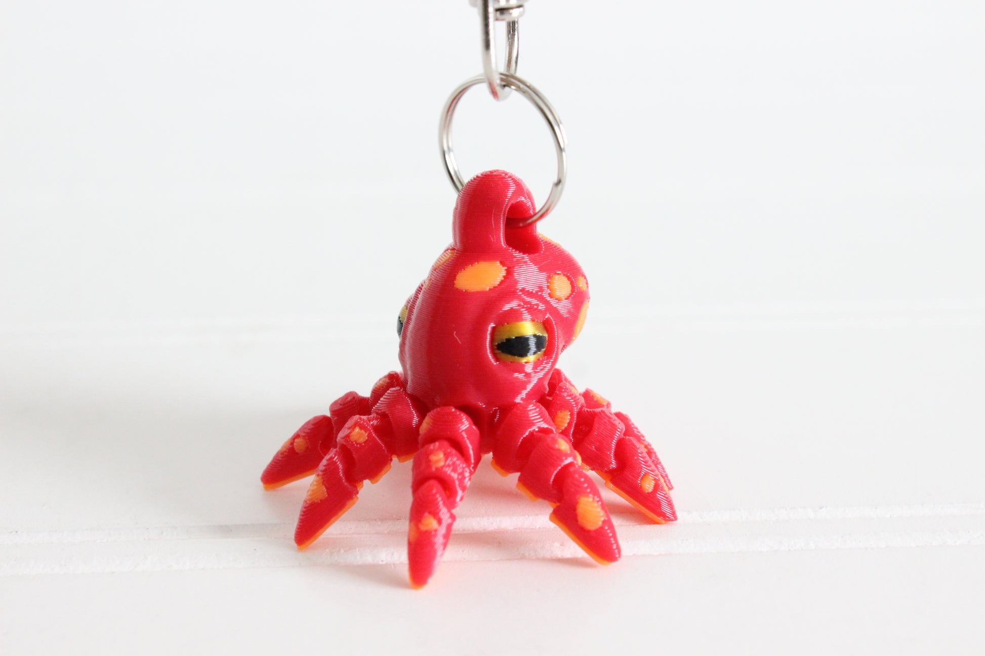 3D-printed octopus with curled tentacles keychain with a silver swivel quick-clip on a white background.