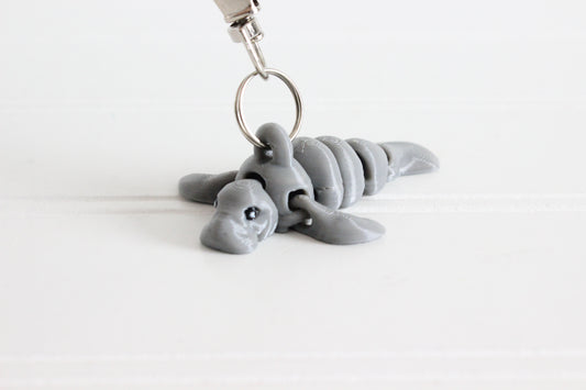 3D-printed gray manatee keychain with a silver swivel quick-clip on a white background.