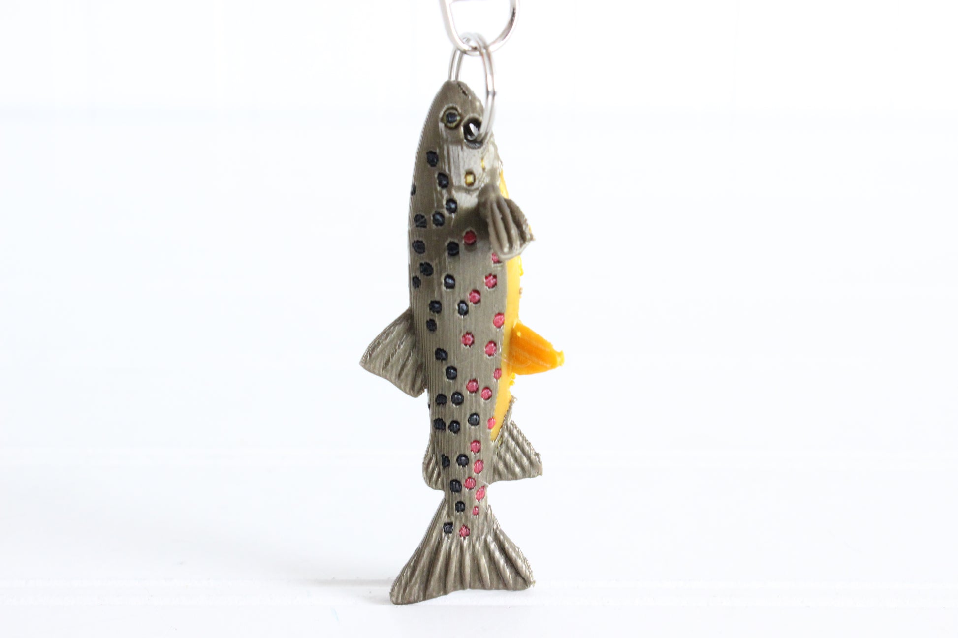 3D-printed brown trout with spotted markings keychain with a silver swivel quick-clip on a white background.
