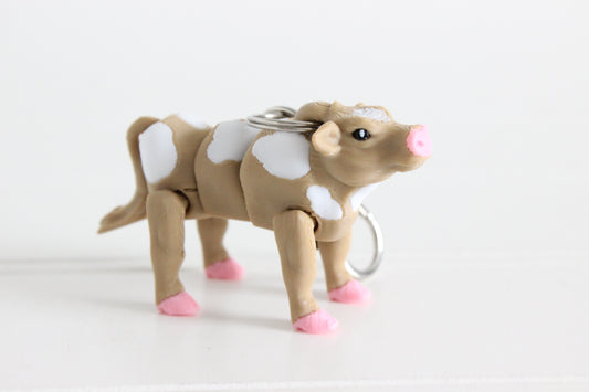 3D-printed brown-and-white cow keychain with a silver swivel quick-clip on a white background.