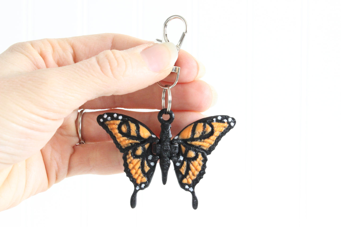 3D-printed orange-and-black monarch butterfly keychain with a silver swivel quick-clip on a white background.