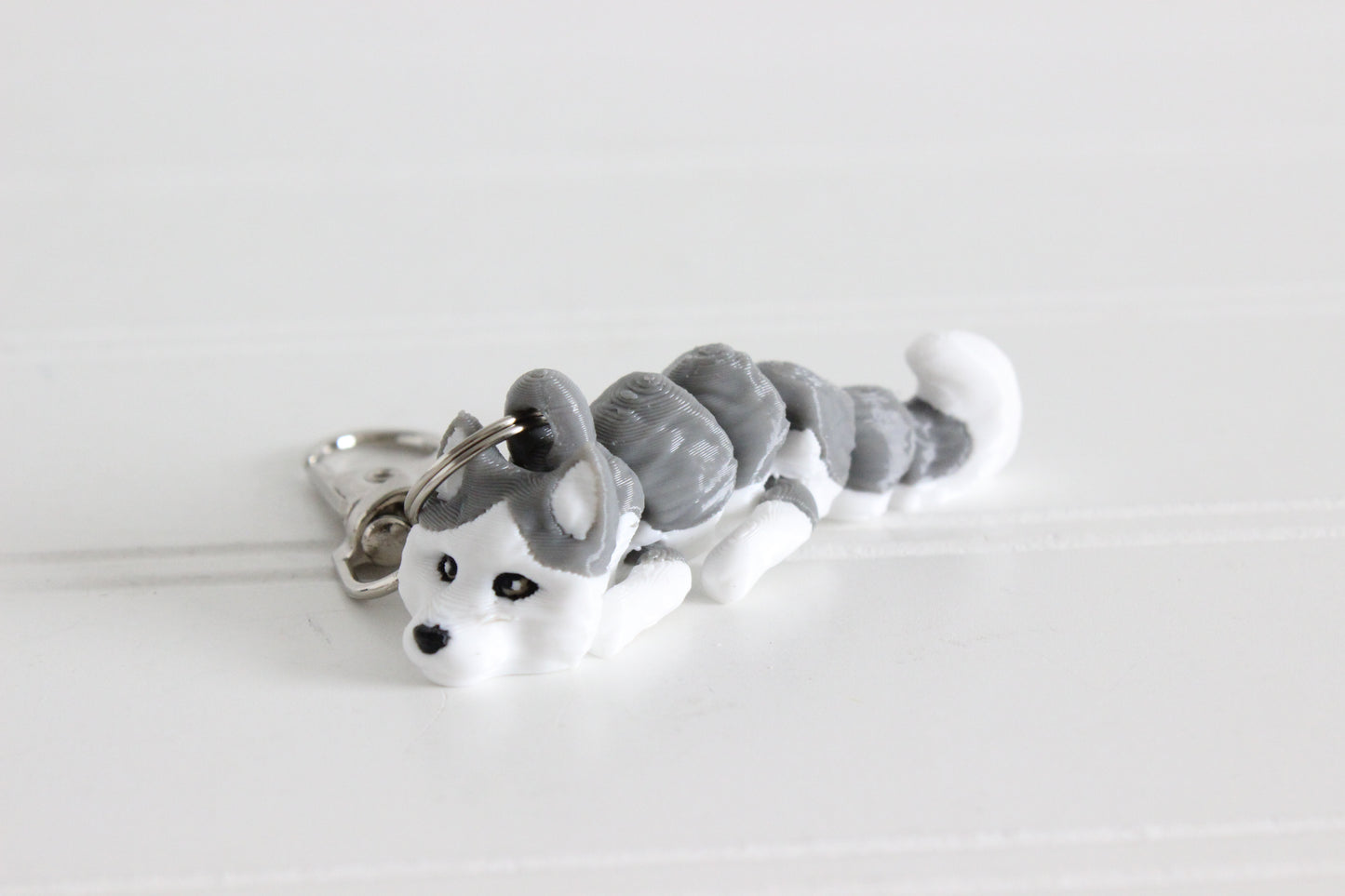 3D-printed gray-and-white husky keychain with a silver swivel quick-clip on a white background.