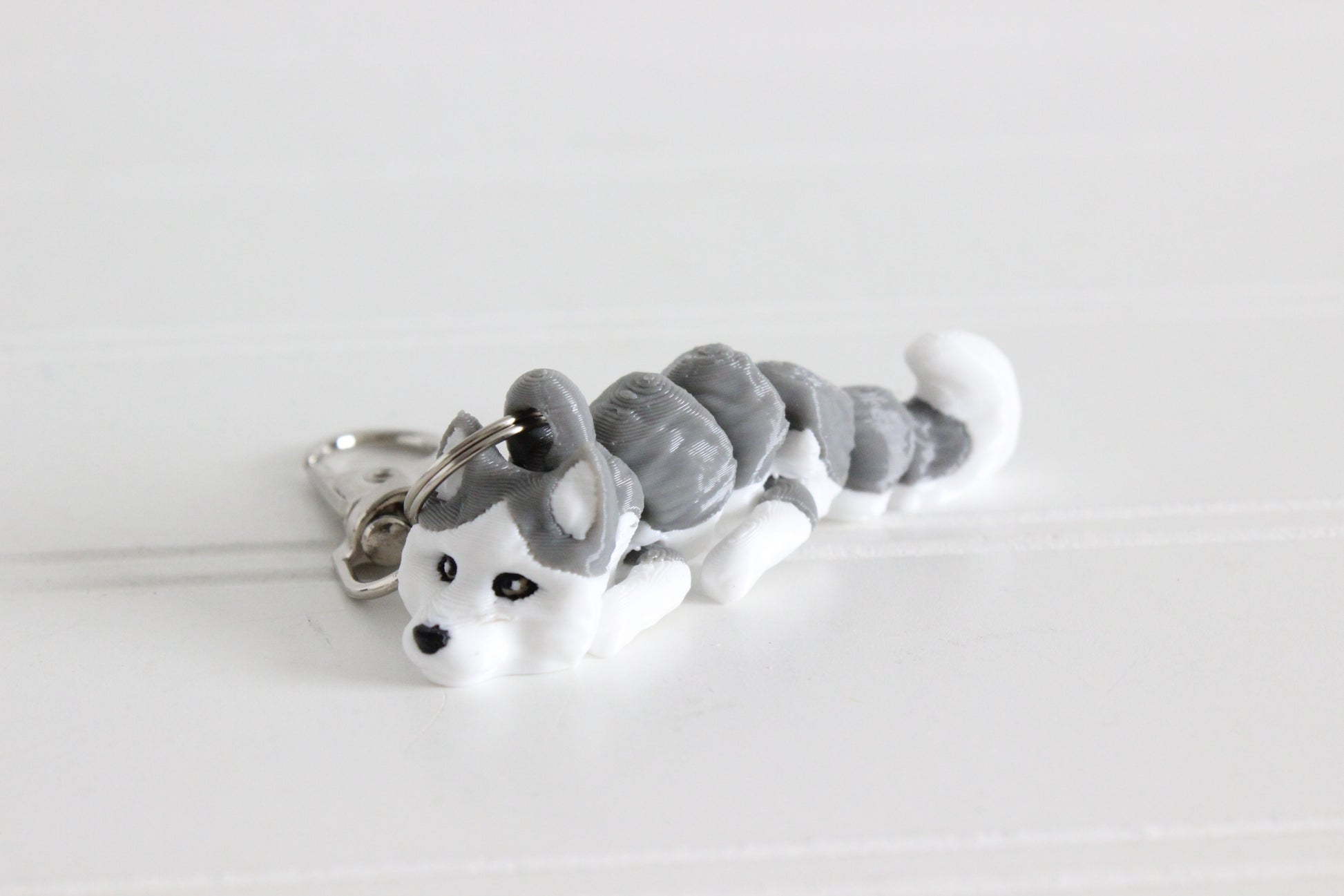 3D-printed gray-and-white husky keychain with a silver swivel quick-clip on a white background.