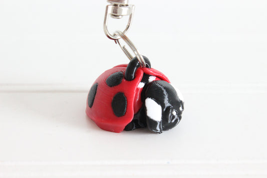 3D-printed red-and-black ladybug keychain with a silver swivel quick-clip on a white background.