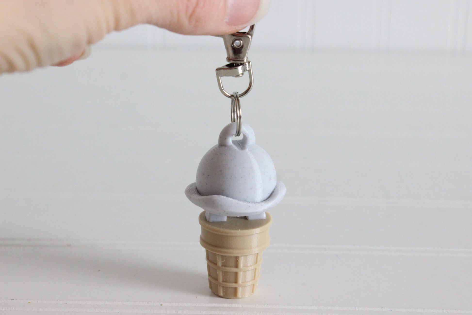 3D-printed cookies-and-cream ice cream cone keychain with a metal key ring on white.