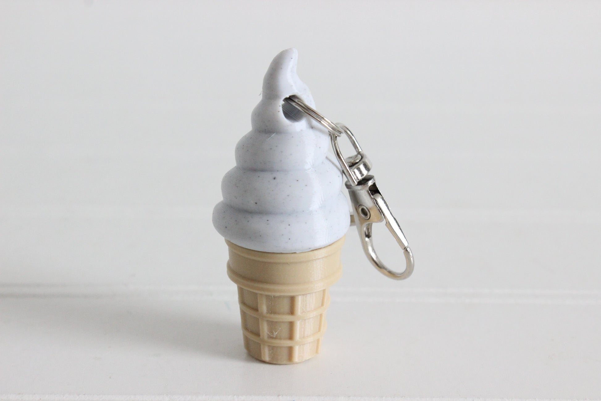 3D-printed cookies-and-cream soft-serve ice cream cone keychain with a metal key ring.