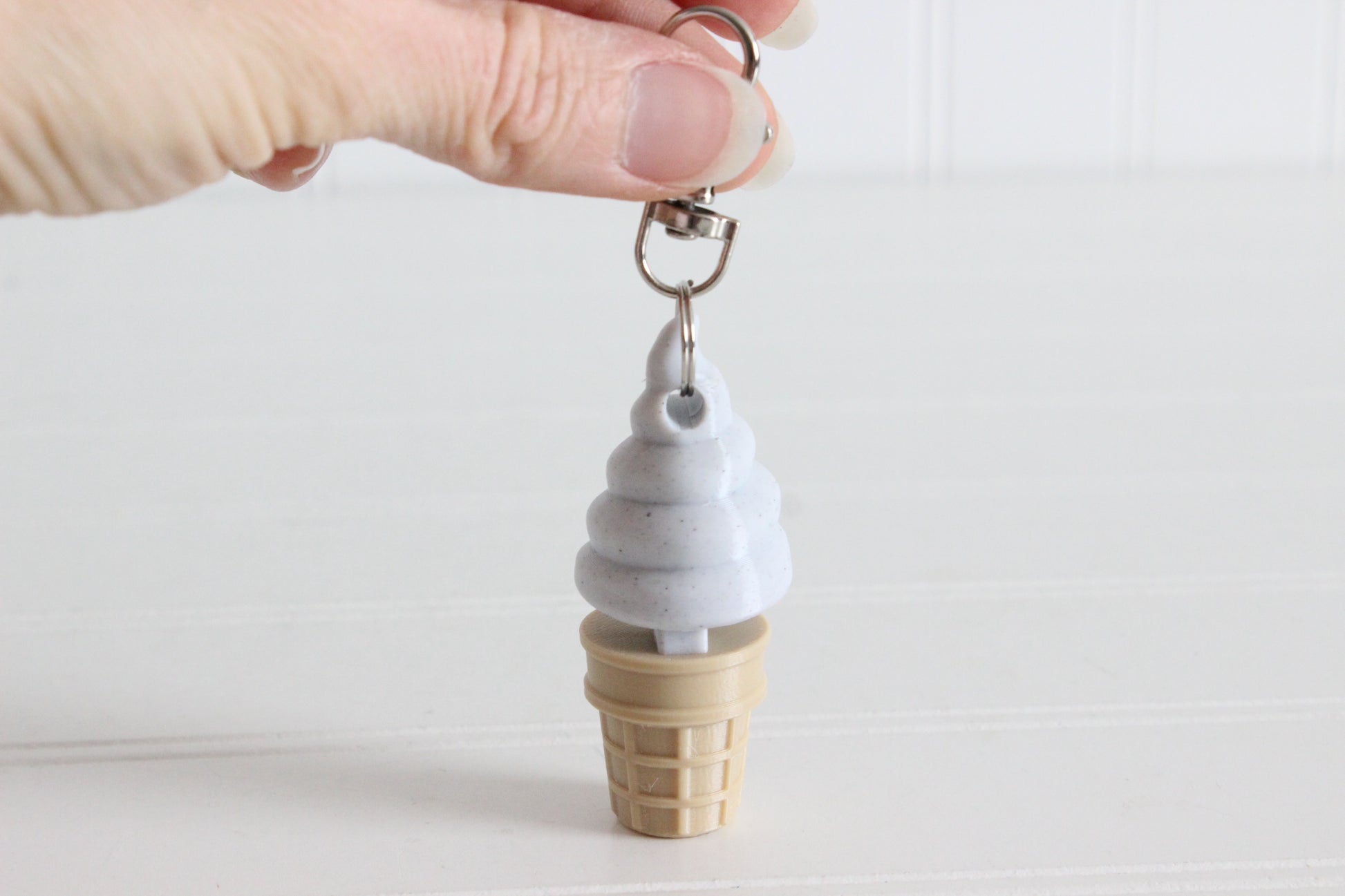 Alternate view of the 3D-printed cookies-and-cream soft-serve ice cream cone keychain showing its shape, color, and key-ring attachment.