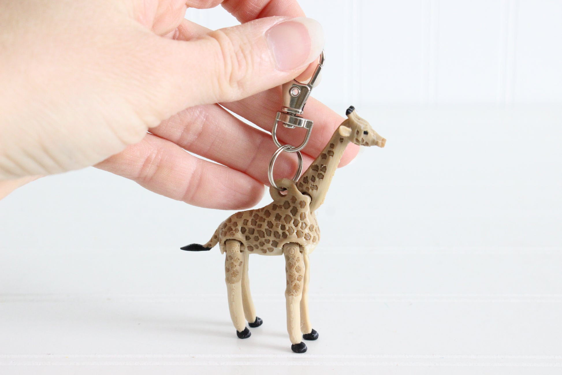 Alternate view of the 3D-printed tan giraffe with brown spots keychain showing its sculpted details and segmented design.