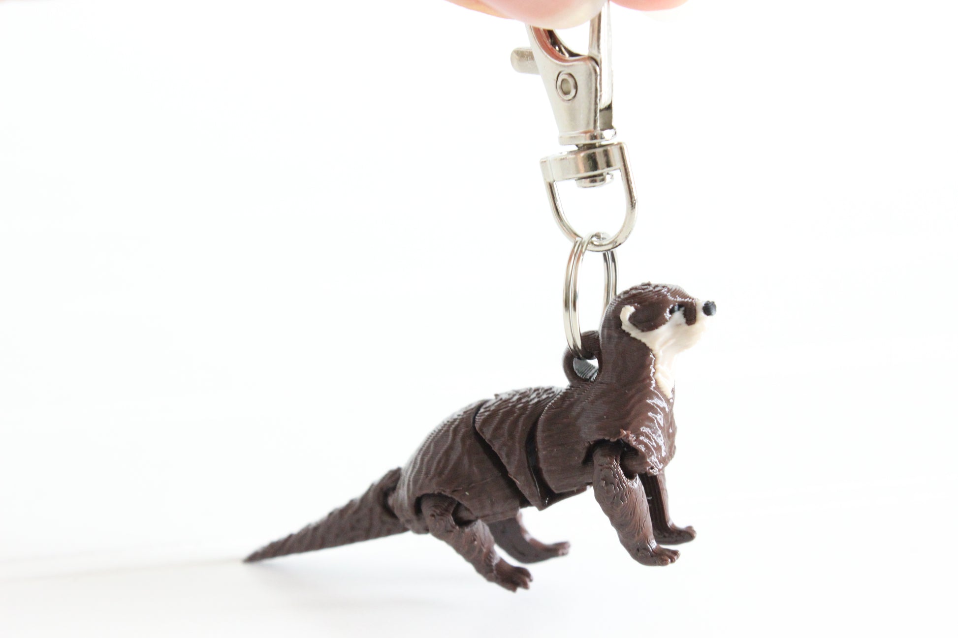 3D-printed brown river otter keychain with a silver swivel quick-clip on a white background.