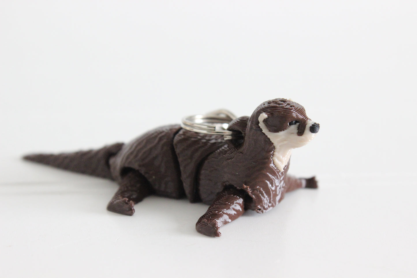 Alternate view of the 3D-printed river otter keychain showing its sculpted details and segmented design.
