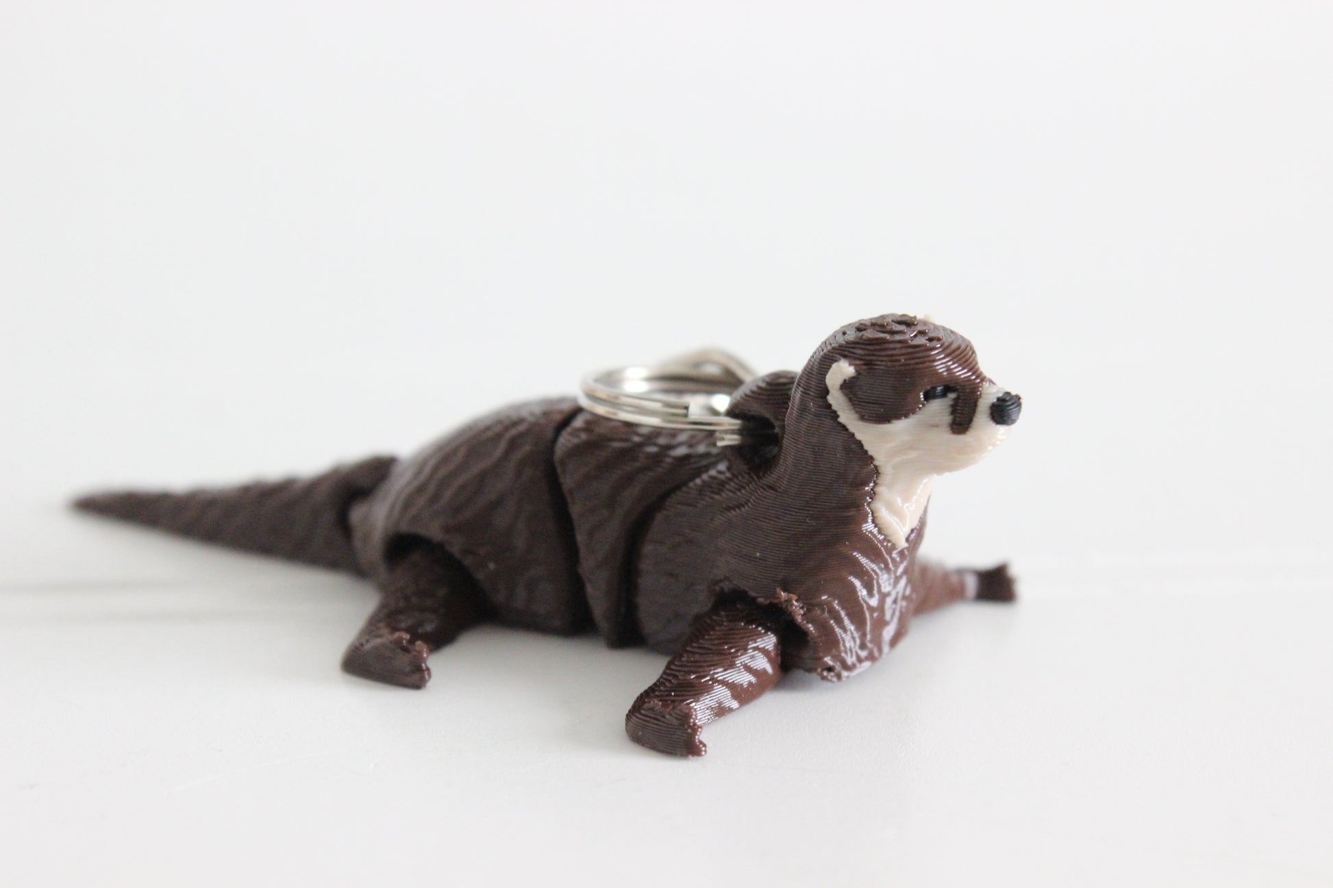 Alternate view of the 3D-printed river otter keychain showing its sculpted details and segmented design.