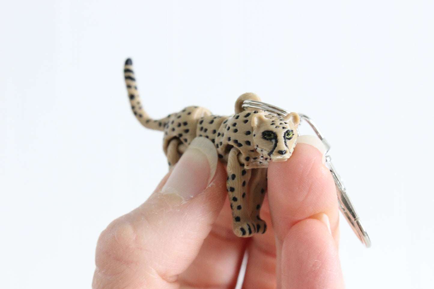Articulated tan cheetah keychain with black spots and a silver swivel quick-clip.