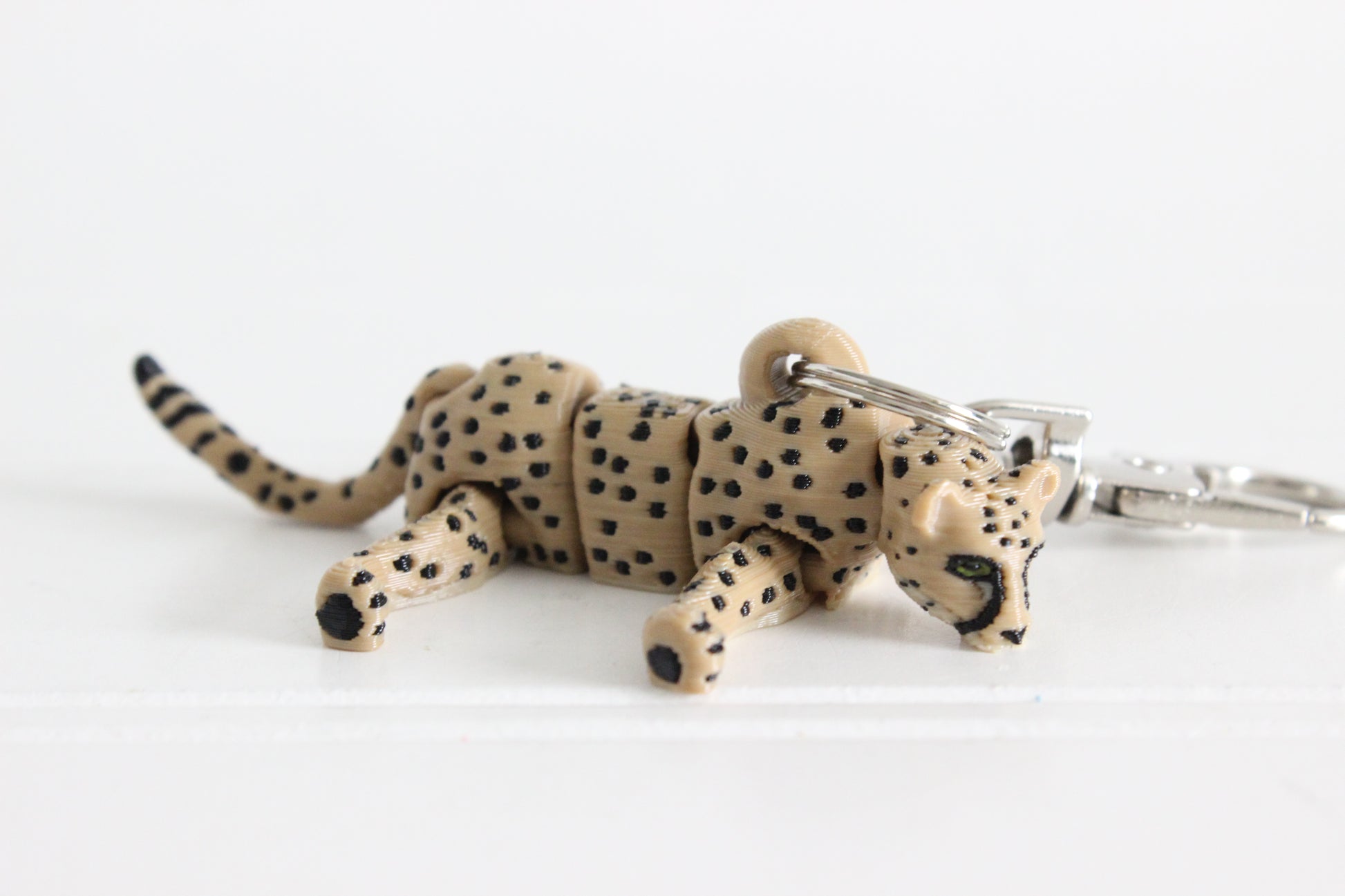 Alternate view of the 3D-printed tan cheetah with black spots keychain showing its sculpted details and segmented design.