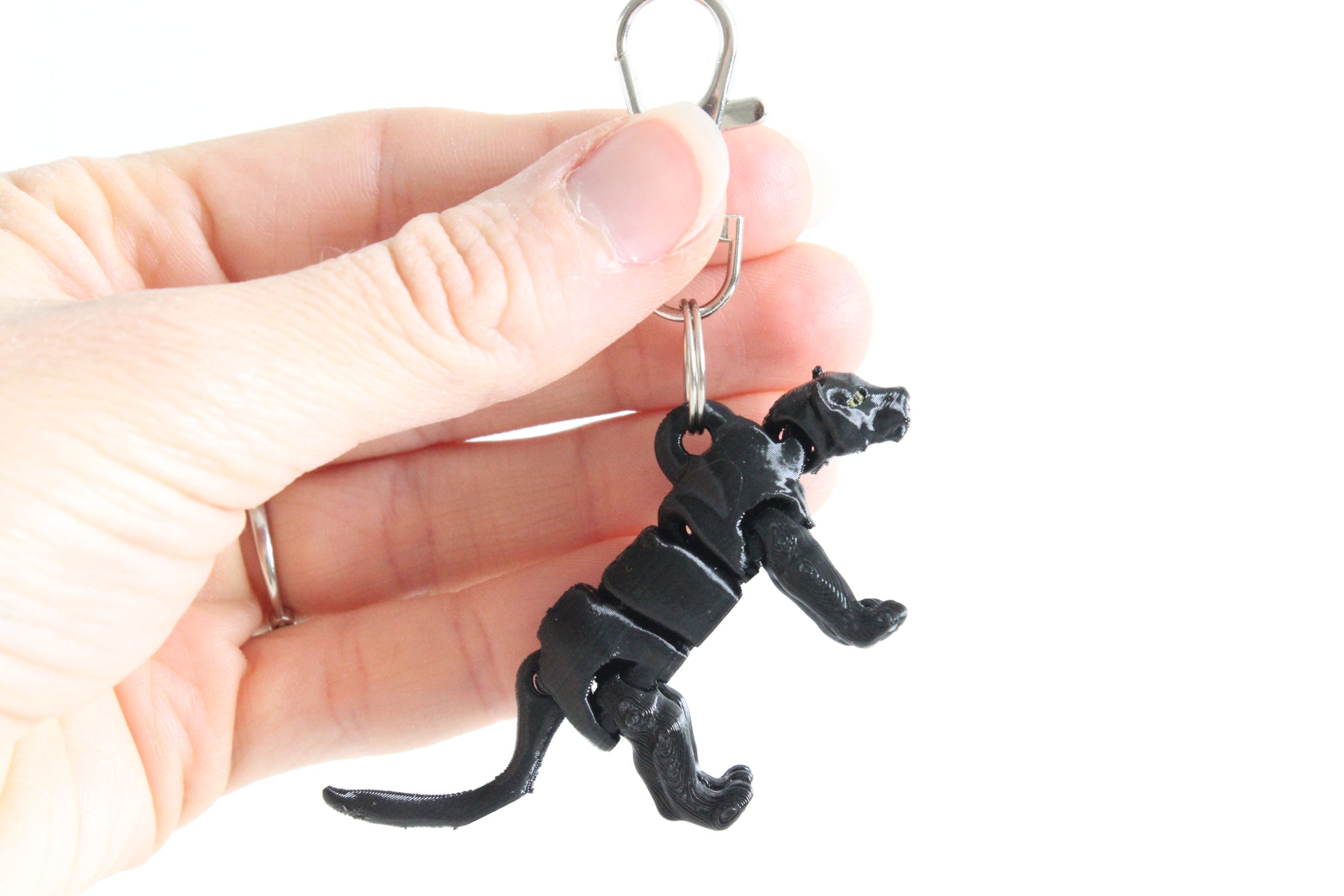 Hand holding articulated black panther keychain for size reference.