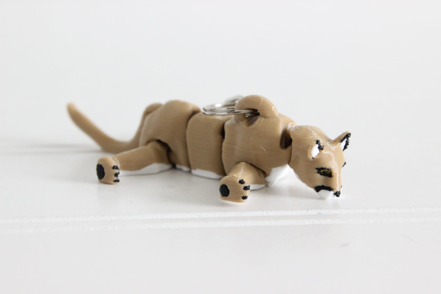 Articulated Mountain Lion keychain posed in a sitting position, showing flexible joints and textured brown fur.