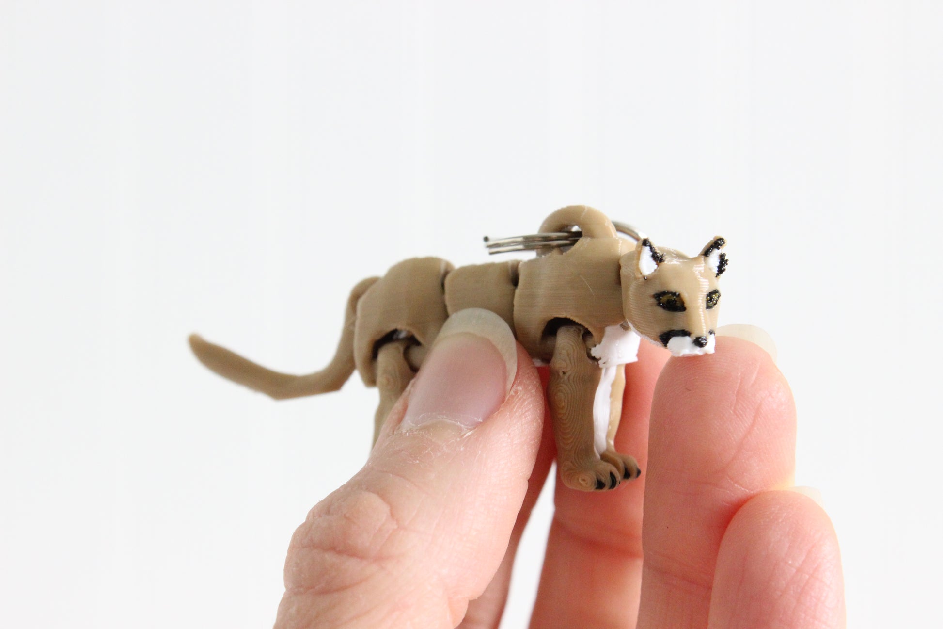 Close-up of the articulated mountain lion keychain showing sculpted facial features, pointed ears, and textured fur.