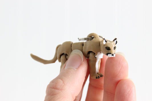 Close-up of the articulated mountain lion keychain showing sculpted facial features, pointed ears, and textured fur.
