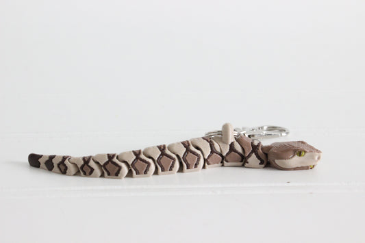 Side view of an articulated copperhead snake keychain with tan and brown banded pattern.