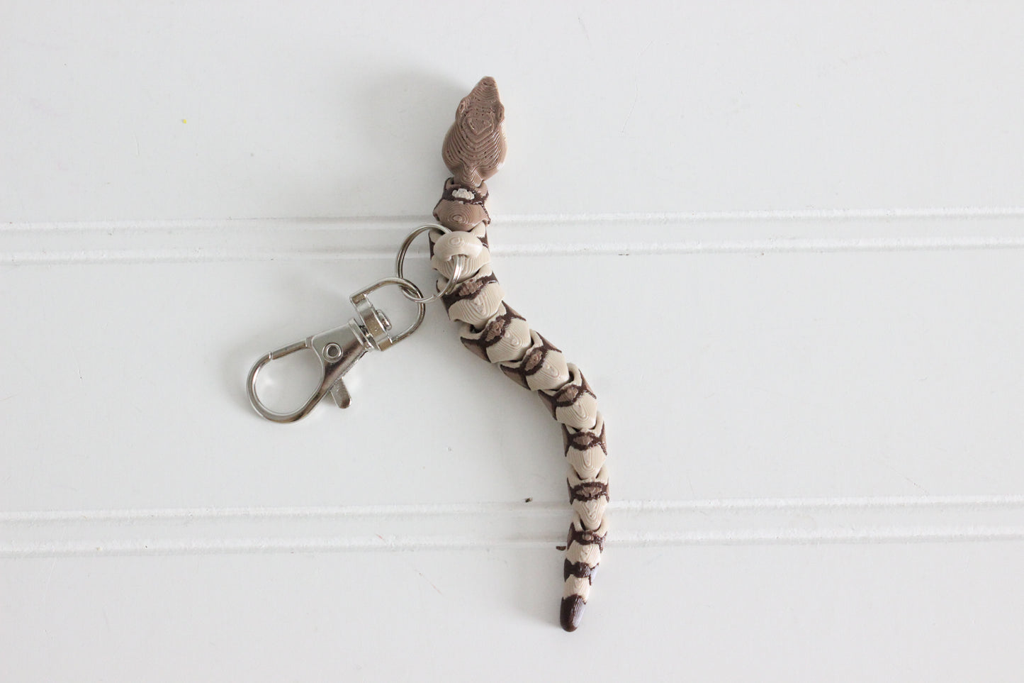 Top view of the articulated copperhead snake keychain showing segmented body and silver swivel quick-clip.