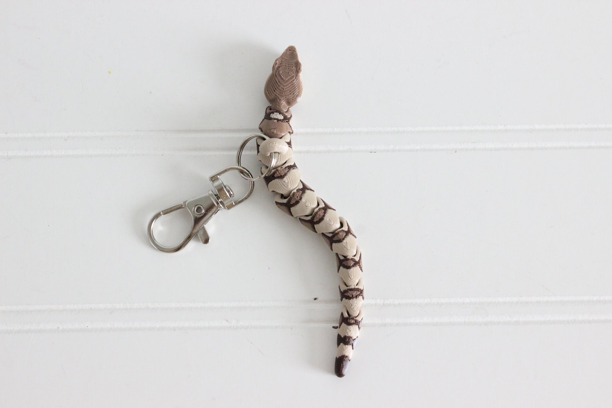 Top view of the articulated copperhead snake keychain showing segmented body and silver swivel quick-clip.