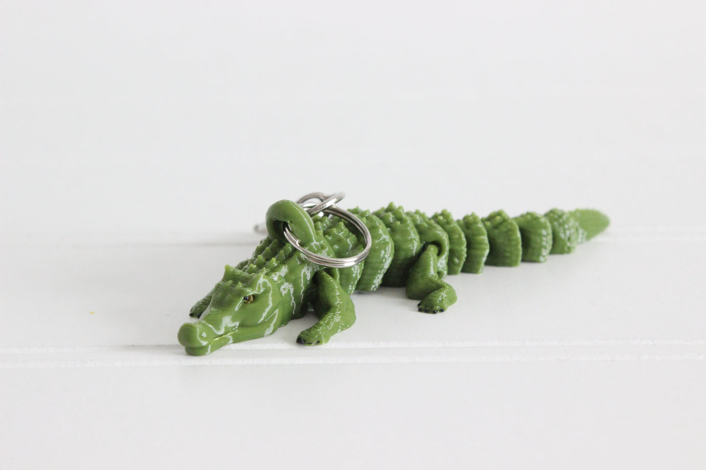 Green 3D-printed alligator keychain with textured scales and a silver swivel quick-clip.