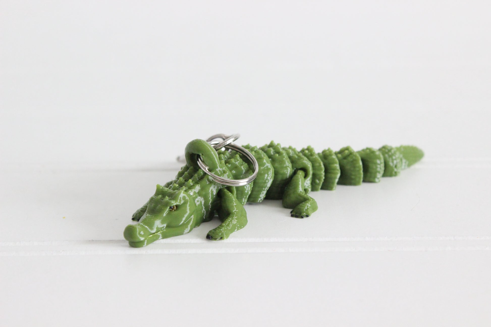 Green 3D-printed alligator keychain with textured scales and a silver swivel quick-clip.