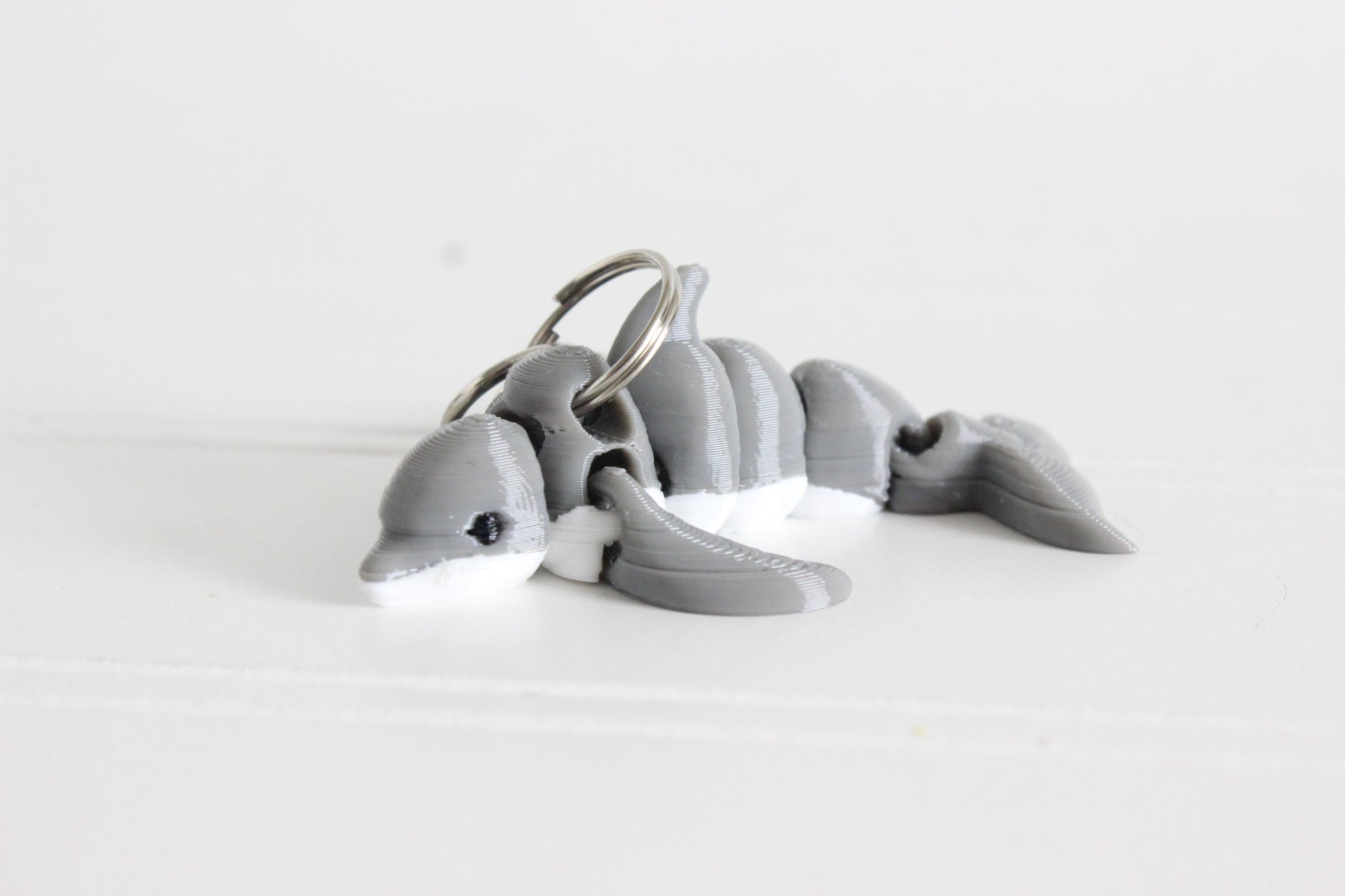3D-printed gray dolphin keychain with a silver swivel quick-clip on a white background.
