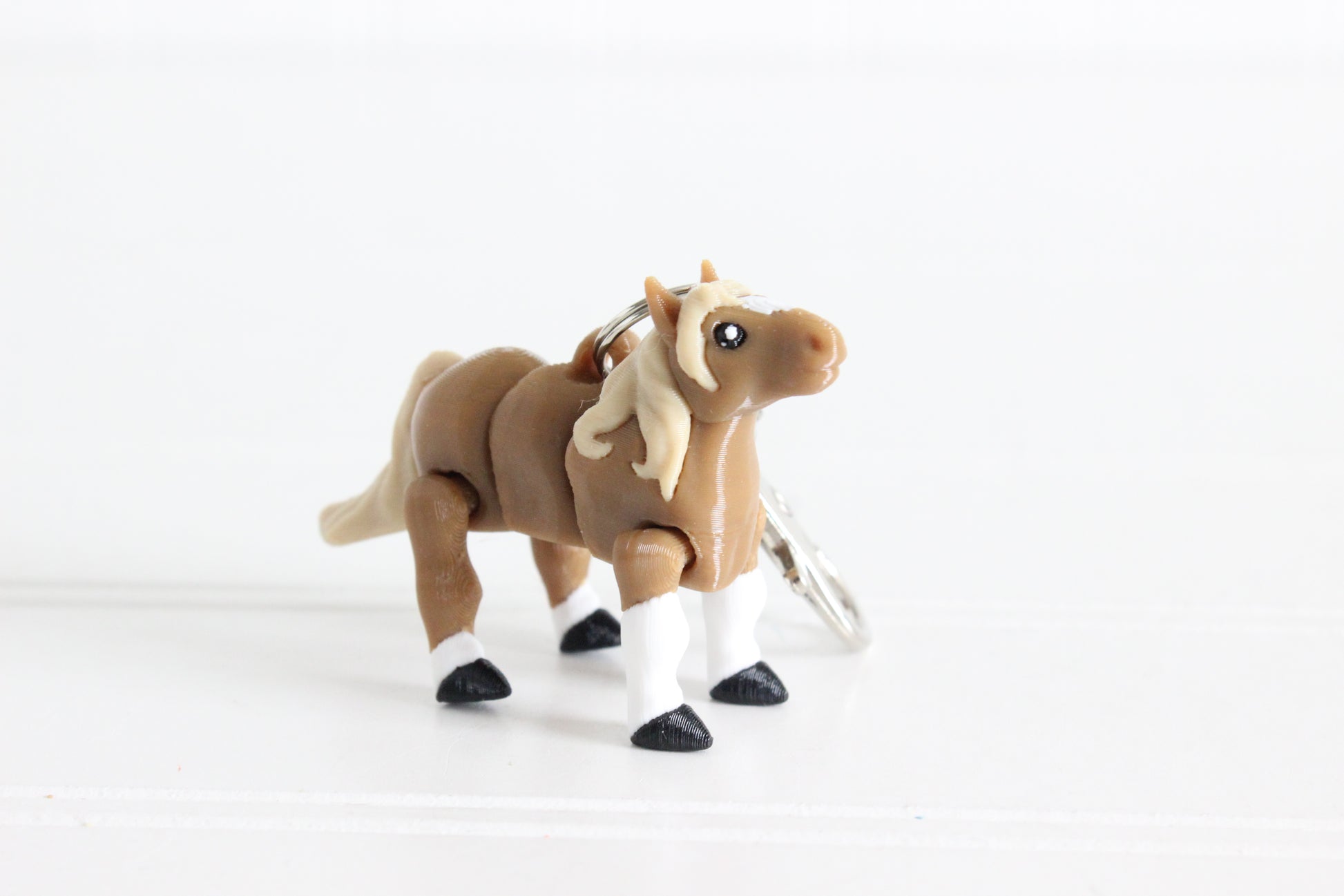 3D-printed brown horse with a blonde mane keychain with a silver swivel quick-clip on a white background.