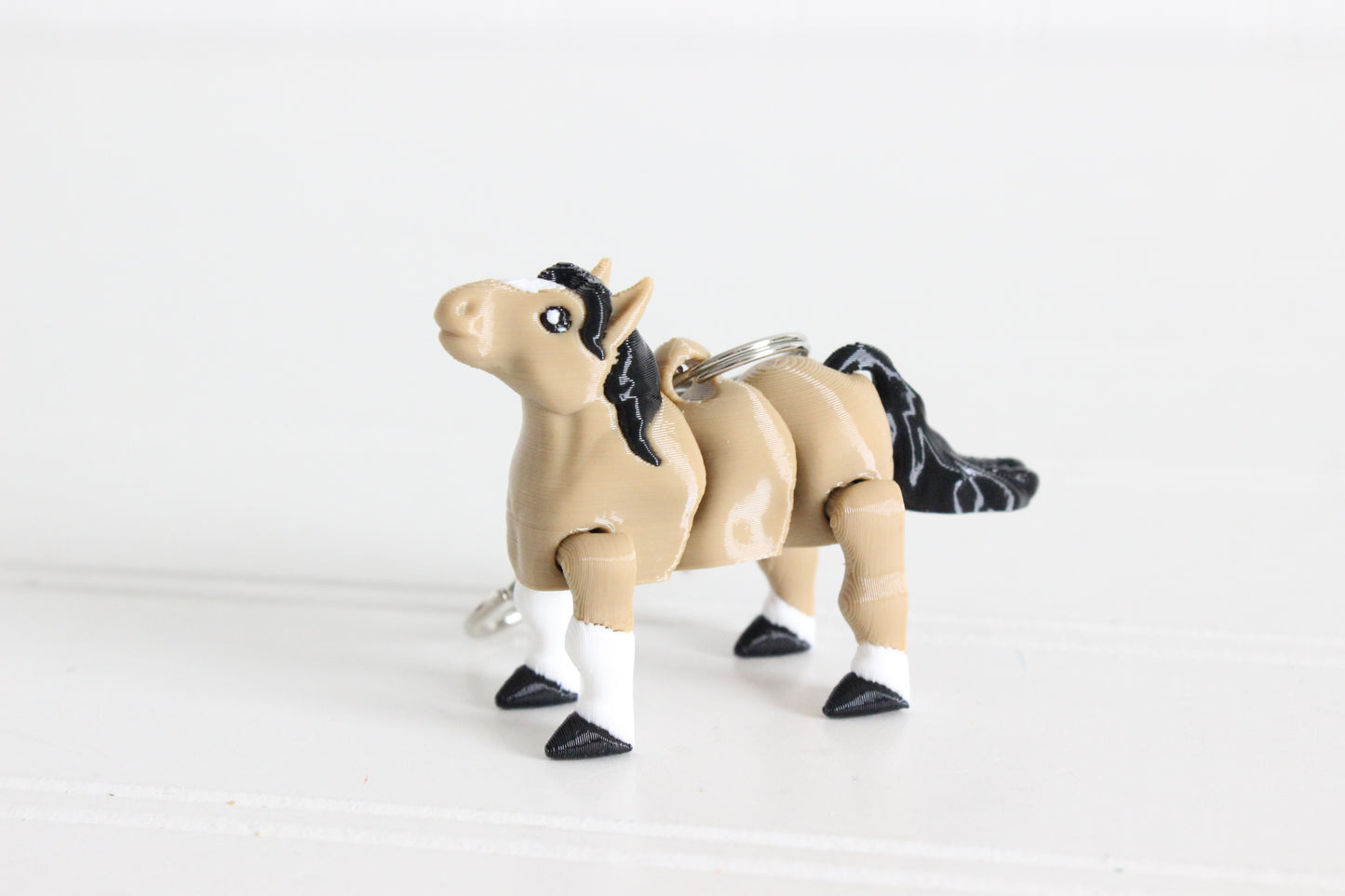 3D-printed brown horse with a black mane keychain with a silver swivel quick-clip on a white background.