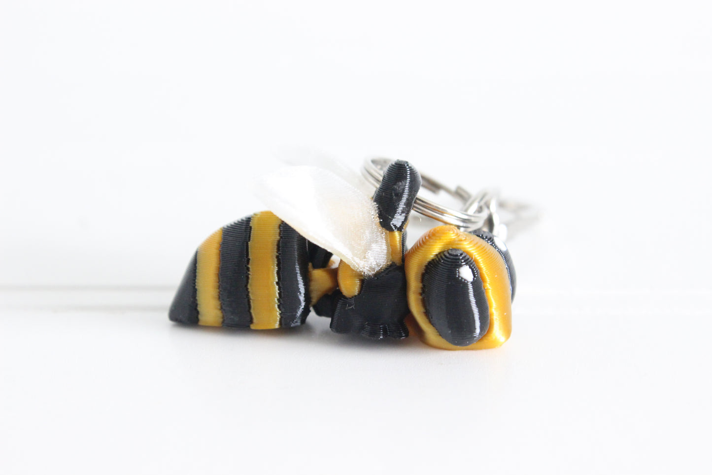 Alternate view of the 3D-printed yellow-and-black bee with translucent wings keychain showing its sculpted details and segmented design.