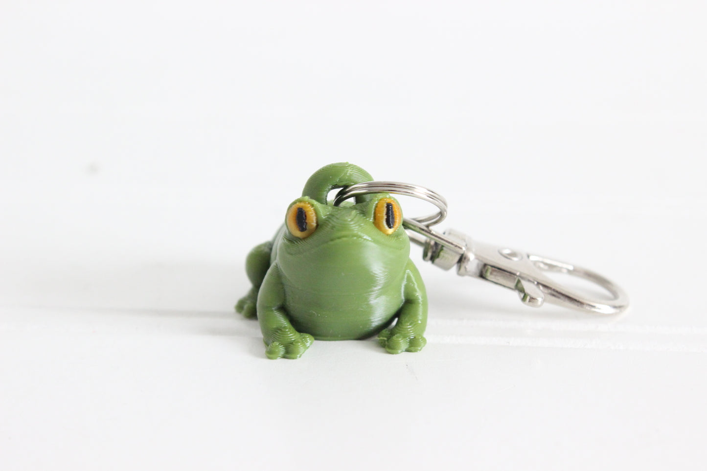 Alternate view of the 3D-printed green frog keychain showing its sculpted details and segmented design.