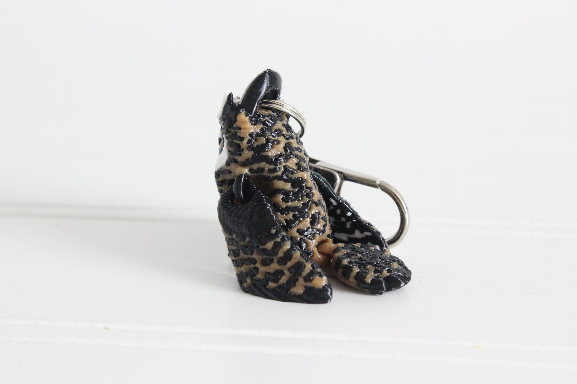 Alternate view of the 3D-printed brown great horned owl keychain showing its sculpted details and segmented design.
