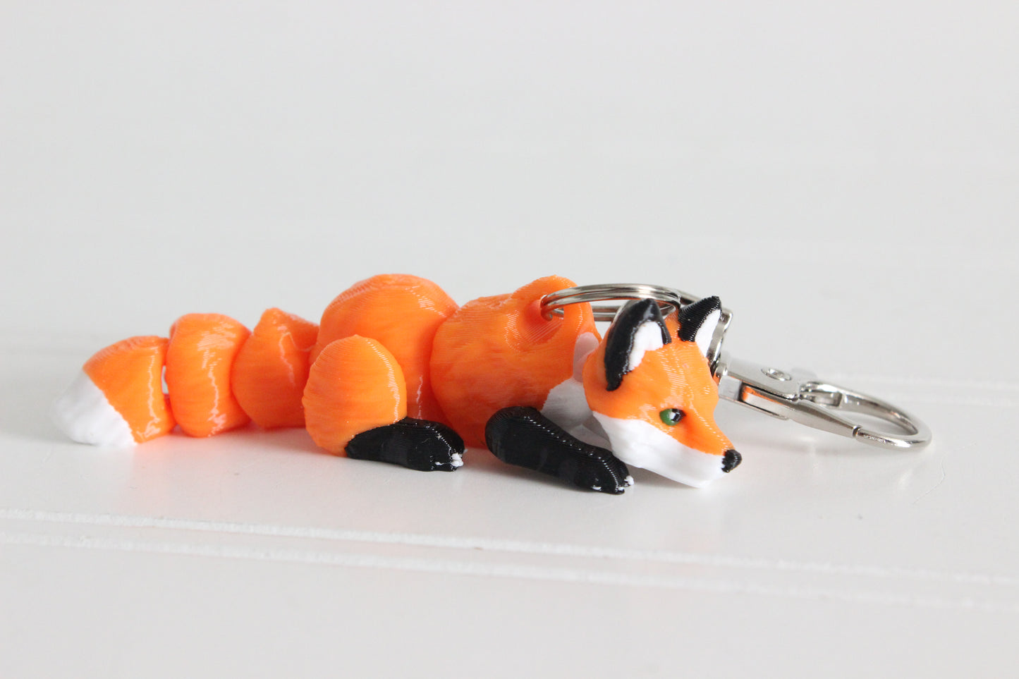 3D-printed orange-red fox keychain with a silver swivel quick-clip on a white background.