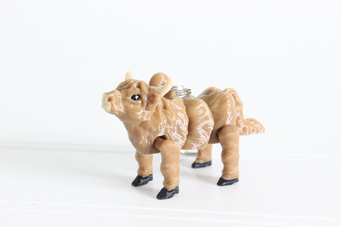 3D-printed shaggy brown Highland cow keychain with a silver swivel quick-clip on a white background.