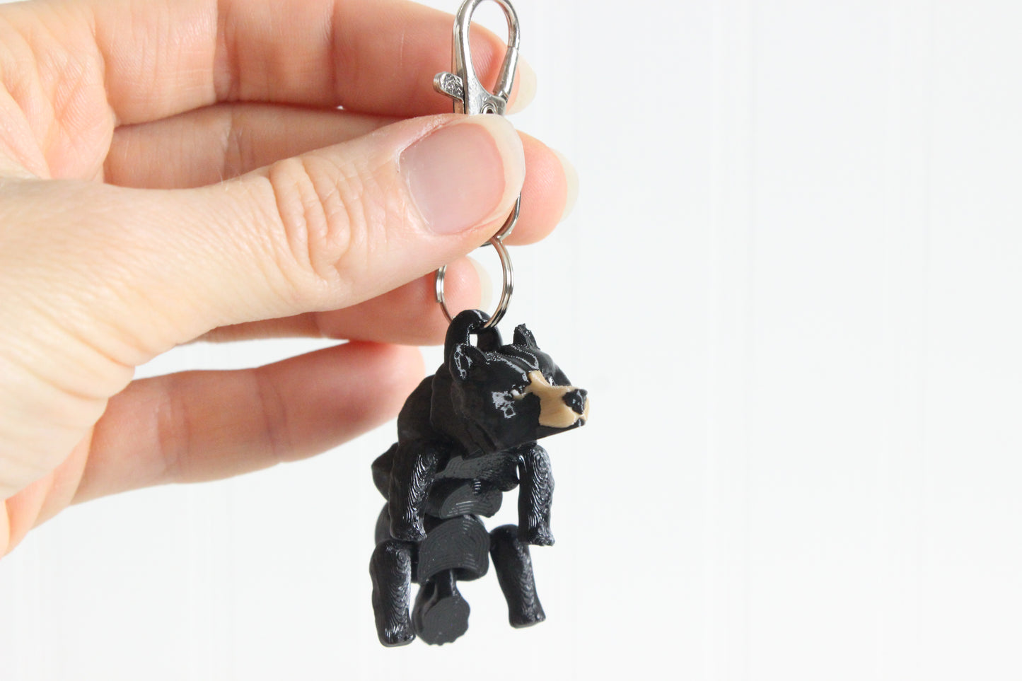 Alternate view of the 3D-printed black bear keychain showing its sculpted details and segmented design.