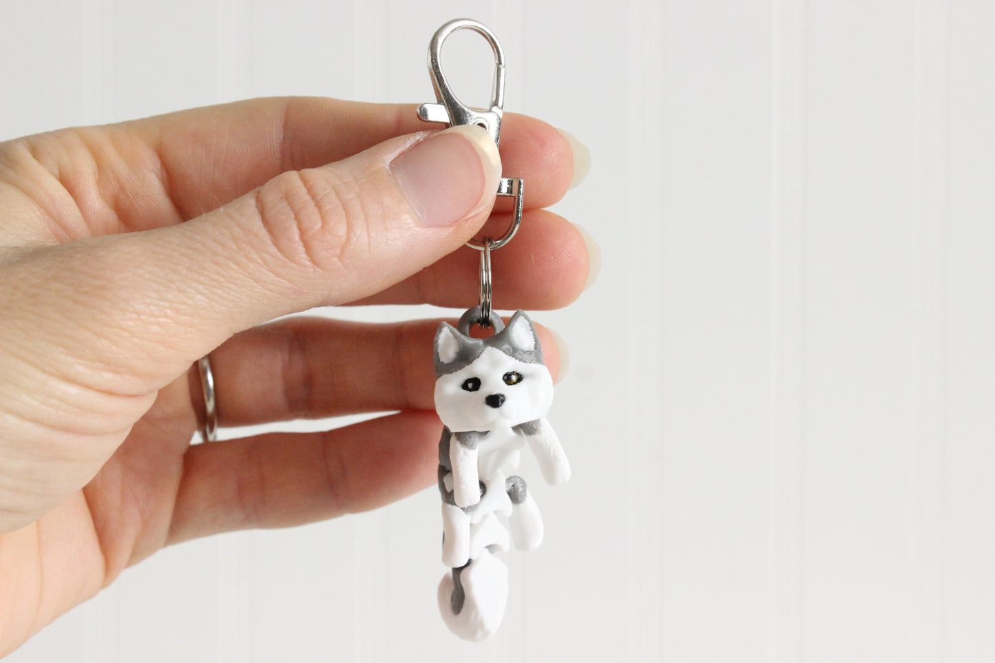 Alternate view of the 3D-printed gray-and-white husky keychain showing its sculpted details and segmented design.