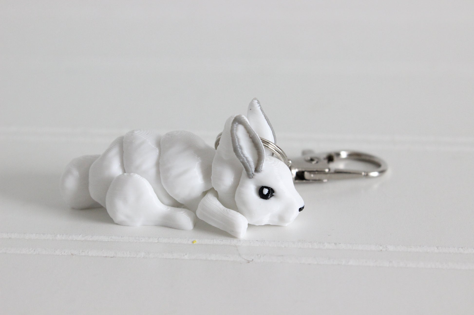 Alternate view of the 3D-printed white snow rabbit keychain showing its sculpted details and segmented design.