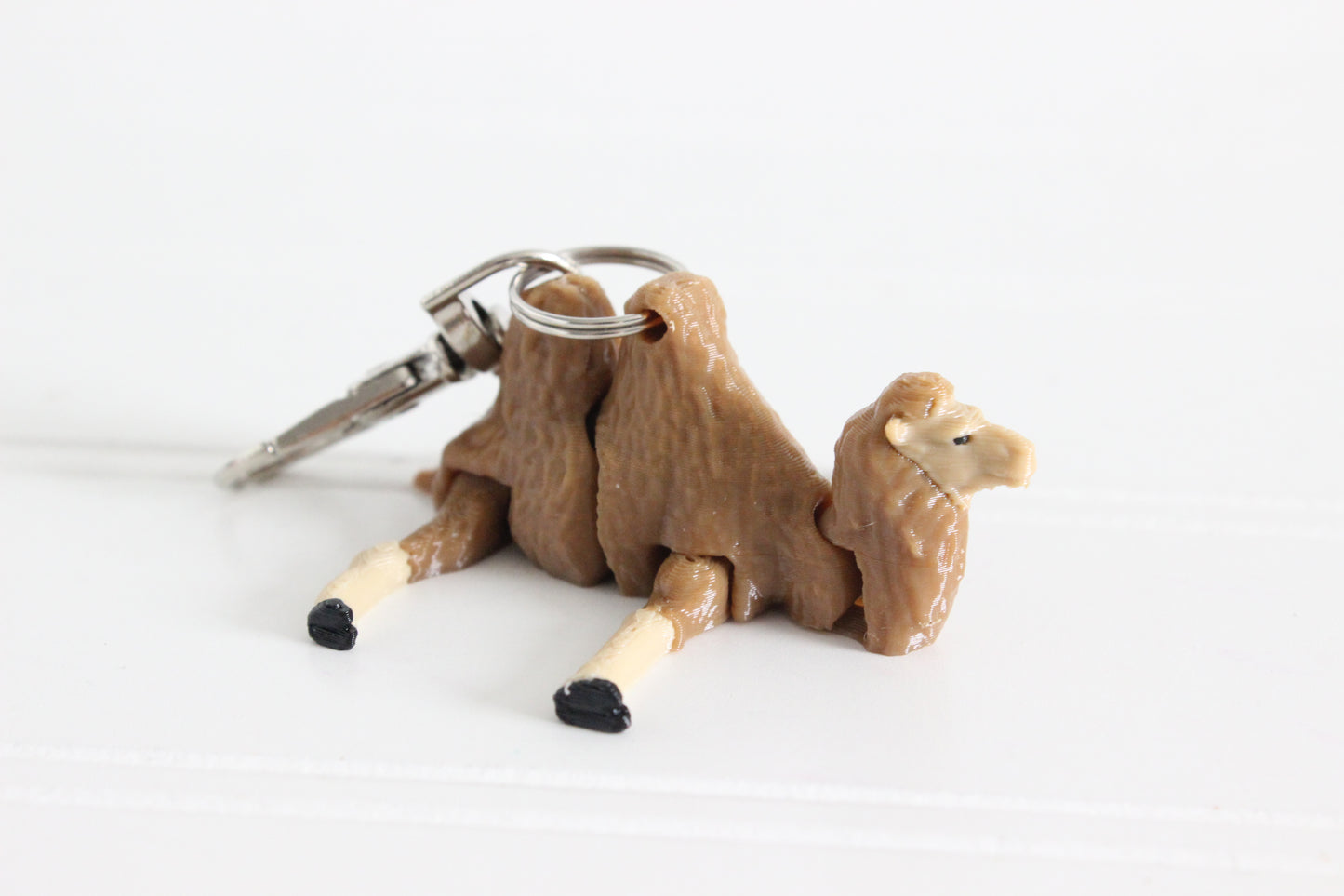 Alternate view of the 3D-printed brown-and-cream camel keychain showing its sculpted details and segmented design.