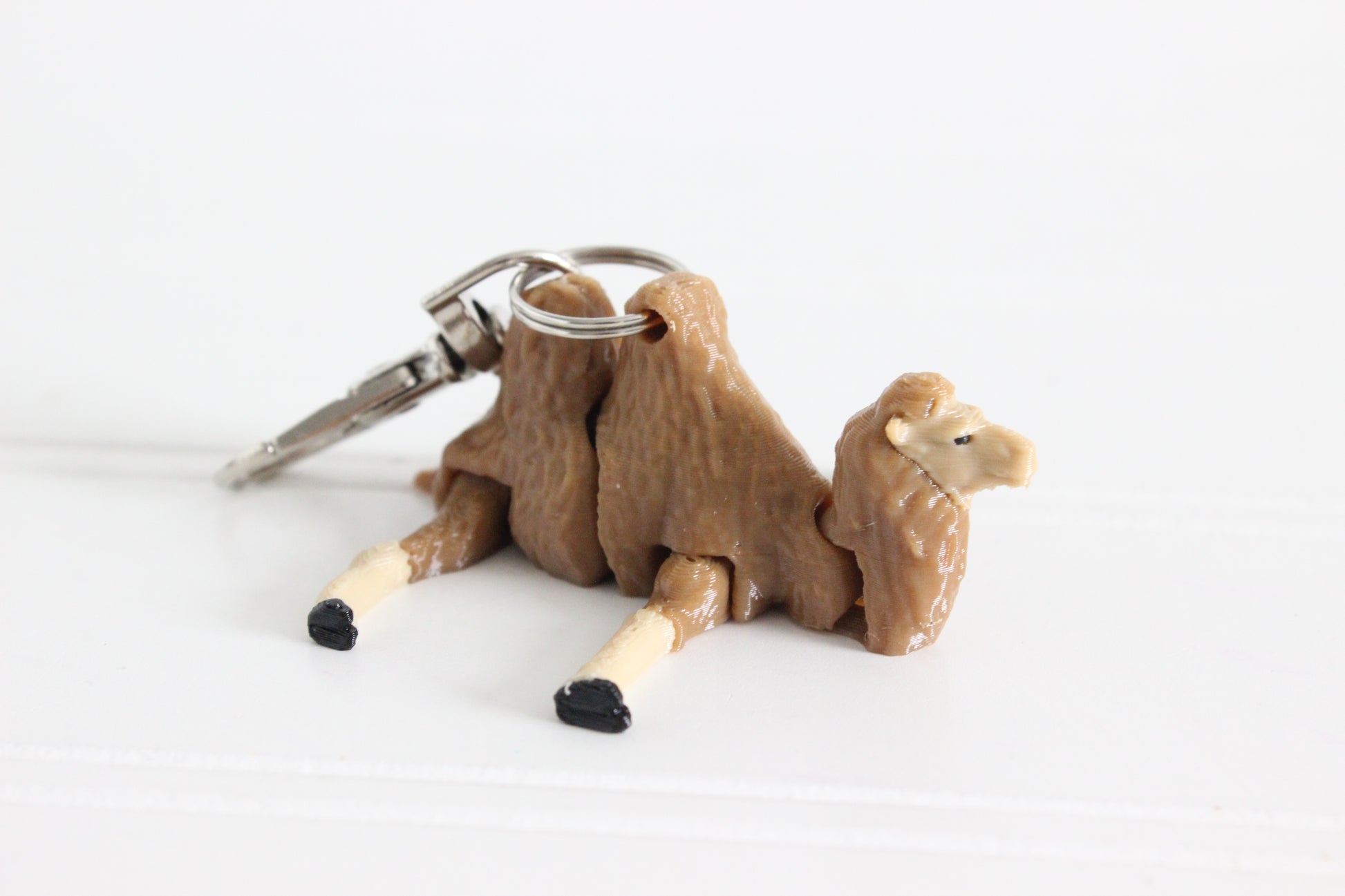 Alternate view of the 3D-printed brown-and-cream camel keychain showing its sculpted details and segmented design.