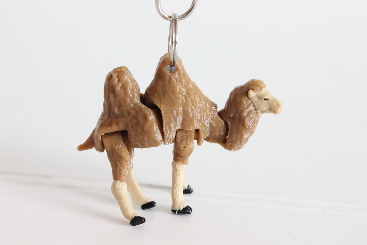 Articulated brown-and-cream camel keychain with textured fur and a silver swivel clip.