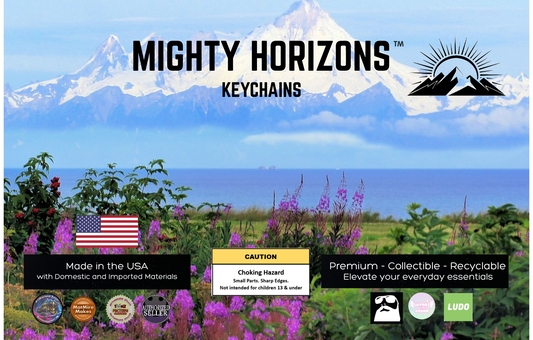 Mighty Horizons Keychains northern retail display sign with snowcapped mountains and wildflowers, U.S.-made materials statement, choking-hazard warning for ages 13 and under, premium collectible recyclable message, and designer attribution logos.